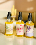 Set of three natural body oils in glass bottles from Be Well Company, featuring soothing and hydrating body elixir formulas.